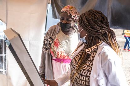 Nikita Laureen, una trabajadora de salud comunitaria en Kibera, Nairobi, ayuda a una vecina a usar la máquina que criba casos de tuberculosis. 