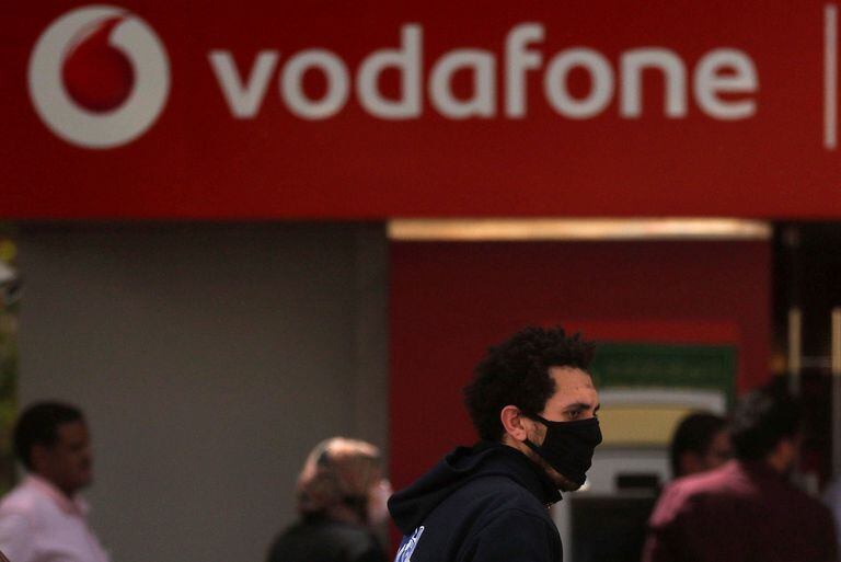 Un hombre pasa junto a un cartel de Vodafone.