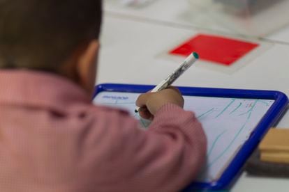 Un niño escribe en una pizarra.