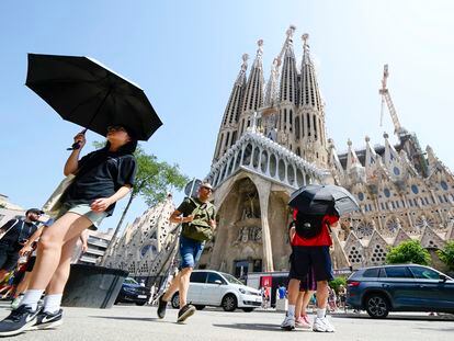 Una turista se protege del sol ante la Sagrada Familia de Barcelona este lunes, primer día de la ola de calor.