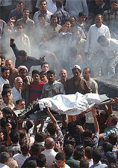 Voluntarios transportan el cadáver de un iraquí muerto por el estallido de un coche bomba en Bagdad.
