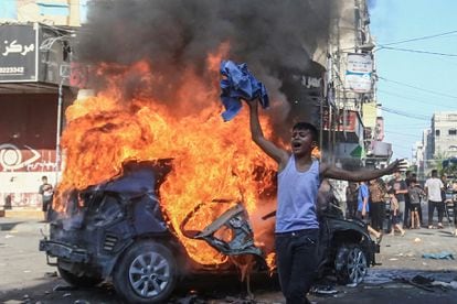 Un niño palestino, junto a un vehículo israelí en llamas que hombres armados palestinos llevaron a Gaza tras infiltrarse en zonas del sur de Israel, el sábado. 