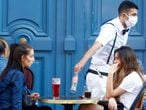 A waiter wearing a face mask serves clients while people eat and have drinks on the terrace of the cafe-restaurant  in Paris on June 2, 2020, as cafes and restaurants reopen in France with the easing of lockdown mesures taken to curb the spread of the COVID-19 pandemic, caused by the novel coronavirus. French cafes and restaurants reopened their doors on June 2 as the country took its latest step out of coronavirus lockdown, with clients seizing the chance to bask on sunny terraces after 10 weeks of closures to fight the outbreak.



 (Photo by Mehdi Taamallah/NurPhoto via Getty Images)