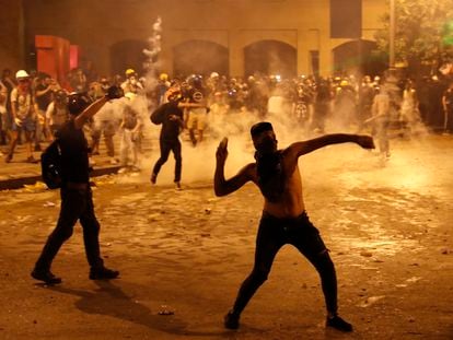 Un manifestante lanza piedras contra la policía antidisturbios libanesa, en Beirut. En vídeo, nueva jornada de enfrentamientos en Beirut.