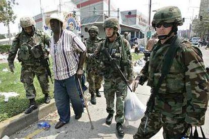 Varios miembros de la Guardia Nacional ayudan a uno de los supervivientes de la catástrofe en Nueva Orleans.