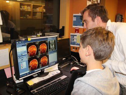 Un investigador enseña a un niño imágenes de su cerebro que acaban de ser tomadas por un escáner.