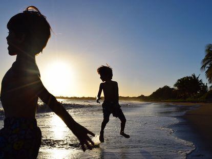 La silueta de dos chicos en la playa de Ponce contra el cielo de una puesta de sol, Puerto Rico.