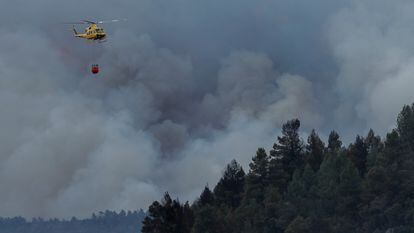 Un helicóptero sobrevolaba el jueves una columna de humo en el incendio forestal en Villanueva de Viver.
