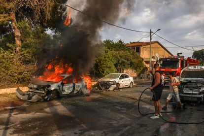 Dos vecinos apagaban las llamas de un vehículo en la ciudad israelí de Ashkelon, este martes, tras un ataque con cohetes lanzados desde Gaza.