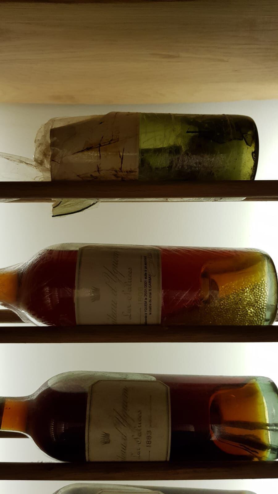 Arriba del todo, la botella original de Chateau d’Yquem de 1806, rota tras un incidente en su almacenaje en 2001. En medio, la botella que contienen el contenido que se recuperó tras el incidente. 