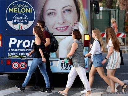 Varias mujeres caminaban el 21 de septiembre junto a un cartel electoral del partido de Giorgia Meloni que mostraba un autobús en Roma.