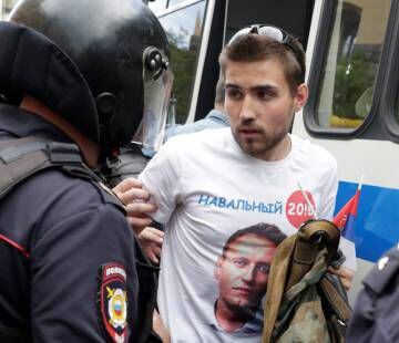 La policía rusa detiene en Moscú a un manifestante que lleva puesta una camiseta con la imagen del opositor Navalni.