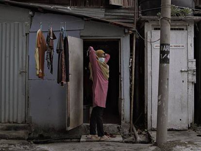 Una mujer indonesia residente en Kuala Lumpur (Malasia), se pone la mascarilla frente a la chabola donde vive. 