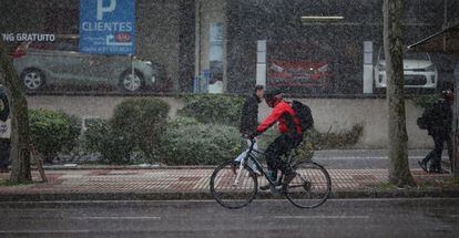 Un joven monta en bicicleta mientras nieva, en Madrid.