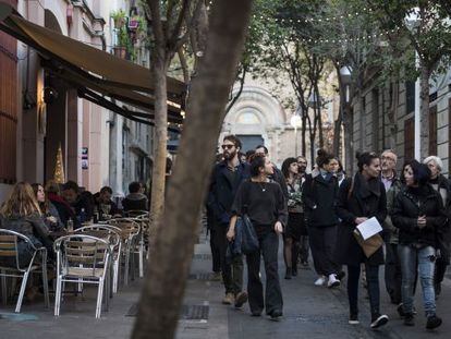 Un grupo de personas pasea por delante de las terrazas de la calle Torrijos, en el barrio de la Vila de Gr&agrave;cia