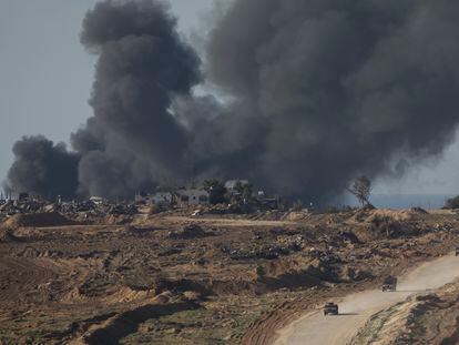 Vehículos israelíes se retiran de la franja de Gaza mientras el humo de los bombardeos sobre el enclave se ve a lo lejos.