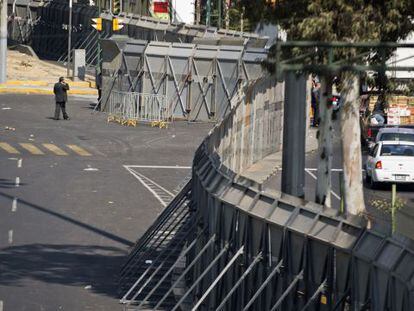 Un hombre camina junto a las vallas que han sido colocadas para resguardar el Congreso mexicano en vísperas de la investidura de Enrique Peña Nieto.