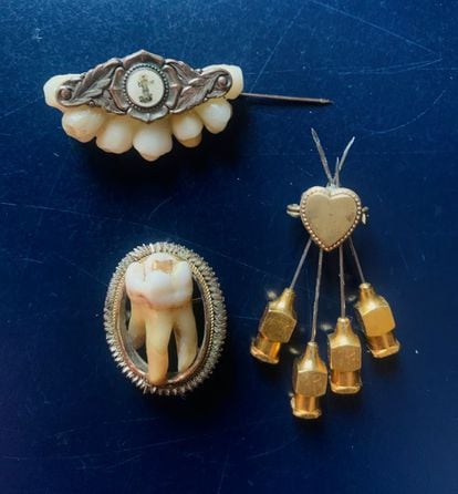 Un broche religioso con dientes postizos, una muela humana real incrustada en un armazón dorado, y un pequeño corazón flechado por cuatro agujas antiguas.