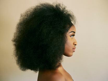 Una mujer con el pelo afro posa para una fotografía.