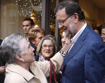 El presidente del Gobierno y candidato a la reelección por el PP, Mariano Rajoy, saluda a una mujer durante un recorrido por las calles de Vigo, dentro de la campaña para las elecciones generales del 20D.