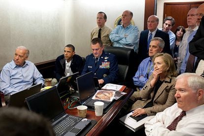 El presidente Barack Obama, junto al vicepresidente Joe Biden (primero por la izquierda) y la secretaria de Estado estadounidense (segunda por la derecha), recibe un nuevo dato de la misión que tenía por objetivo acabar con Bin Laden. En la mesa de la sala, en la que también se encuentran varios miembros del equipo de seguridad nacional de Obama, se encuentra un documento clasificado que ha sido pixelado para evitar su divulgación.