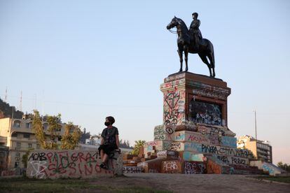 Una mujer toma un descanso junto a la escultura del general Manuel Baquedano en la Plaza Baquedano, Santiago, octubre 2020.