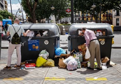Dos hombres intentan dejar su basura en los contenedores llenos de la plaza de Tirso de Molina.
