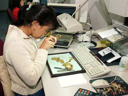 Una empleada de un monte de piedad analiza unas piezas de oro.