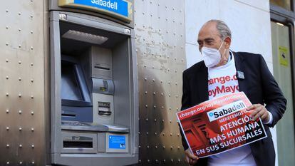 El impulsor de la campaña "Soy mayor no idiota", Carlos San Juan, posa junto a un cajero automático tras registrar 600.000 firmas en el Ministerio Economía para exigir a los bancos una mejor atención.
