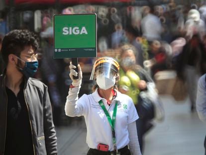 Una funcionaria sostiene un cartel para evitar aglomeraciones en Ciudad de México.