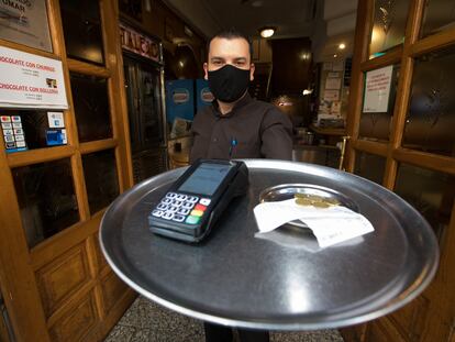 Eduardo, camarero del bar Cantalejo en Madrid, muestra la propina que ha dejado un cliente.