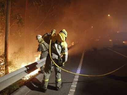 Dos bomberos trabajan en la extinción del incendio de Ribeira en 2013.