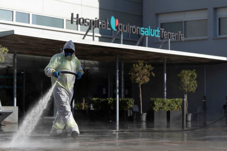 Un operario del servicio de limpieza en Santa Cruz de Tenerife desinfecta el exterior de un hospital de Quirónsalud.