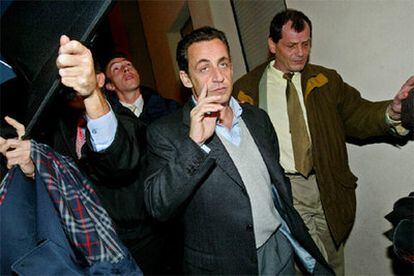 Sarkozy es protegido por sus guardaespaldas durante una visita hoy a un suburbio de París donde se han producido incidentes.