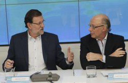 El jefe del Ejecutivo, Mariano Rajoy (i), conversa con el ministro de Hacienda, Crist&oacute;bal Montoro, al inicio de la reuni&oacute;n que preside hoy en la sede nacional del partido para explicar la reforma fiscal aprobada ayer por el Consejo de Ministros. 