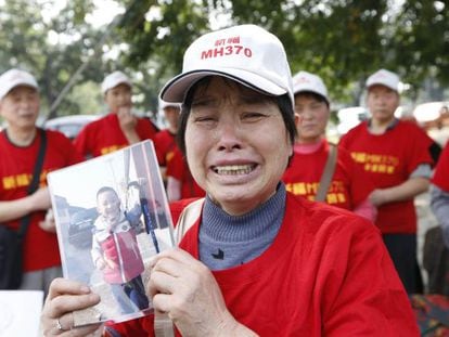 Una mujer muestra la foto de su nieto, cuyo padre desapareció en el vuelo MH370.