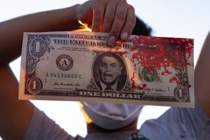 Un manifestante muestra un billete con el rostro de Bolsonaro durante una protesta por la economía en Brasilia. 