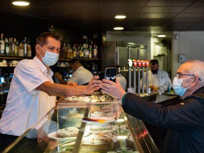 Un camarero escanea el código QR del certificado de vacunación de un cliente en un bar de Barcelona, el pasado viernes.