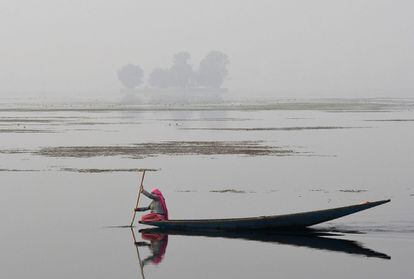Una residente de Cachemira cruza el lago Dal a bordo de una embarcación tradicional, en Srinagar.