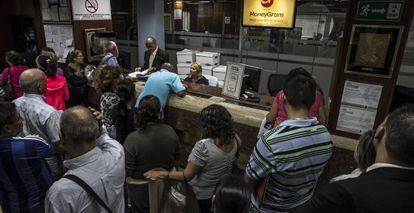 Clientes esperan su turno en una oficina de cambio en Caracas en febrero.