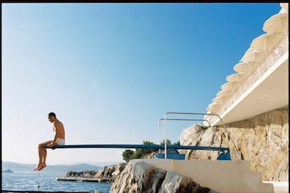 Muros encalados, roca, el azul del cielo, del mar, y un turista sobre un trampolín de piscina. Pocas combinaciones cromáticas funcionan mejor.