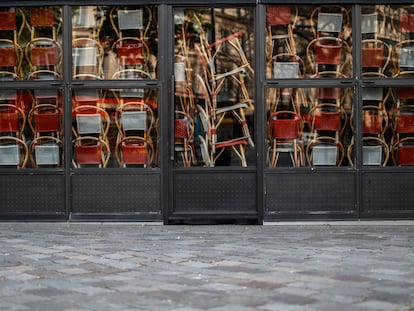 Sillas apiladas tras las puertas de un restaurante cerrado en París a causa de la epidemia de coronavirus
