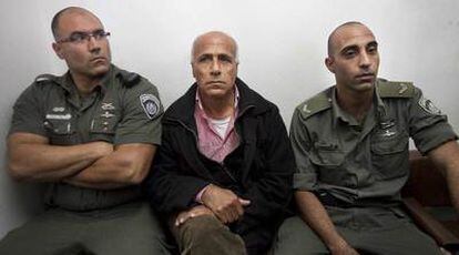 Mordejai Vanunu espera en el juzgado, custodiado por dos guardias.