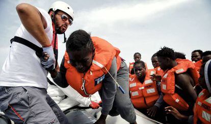 El mediador cultural Salah Dasuki ayuda a subir al dignity I a varios inmigrantes rescatados.