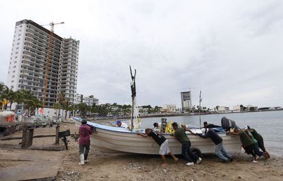 Este domingo, pescadores sacan un bote del agua para resguardarlo antes de que el huracán 'Orlene' toque tierra, en Mazatlán, Estado de Sinaloa (México). El huracán es de nuevo categoría 3 en la escala Saffir-Simpson, como lo era el sábado al pasar frente a las costas de Jalisco. Por unas horas del domingo pasó a categoría 4.