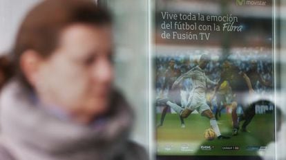 Una mujer pasa frente a un cartel de Movistar TV.