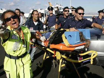 Personal sanitario italiano se abre paso para trasladar al hospital a uno de los pasajeros rescatados.
