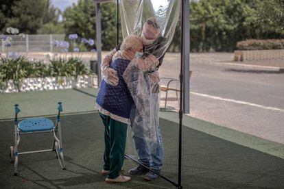 Una interna en una residencia de mayores abraza a su hijo a través de un plástico habilitado para que los familiares se puedan dar su primer abrazo desde hace tres meses.