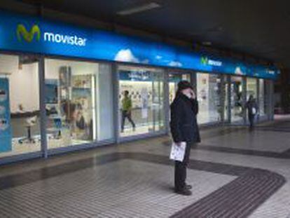 Una persona habla por el m&oacute;vil frente a una tienda de Movistar.