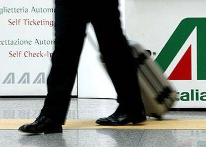 Un pasajero camina delante del emblema de Alitalia en el aeropuerto de Fiumicino (Roma).